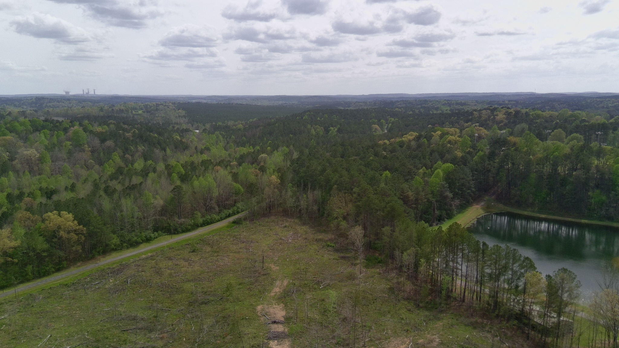 Aerial view showing the trail side edge of the property near a pond and neighboring improvements